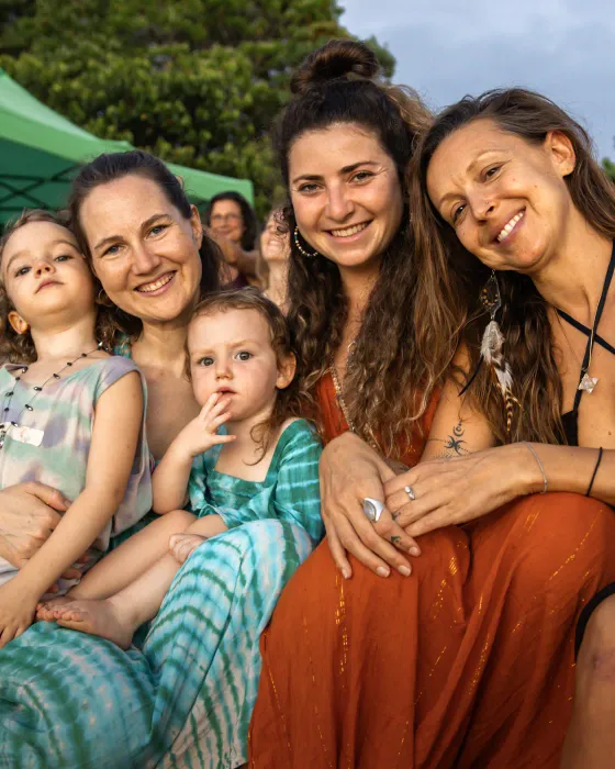 Women and children sitting close together at dusk at Amora, Dominicalito, Costa Rica, smiling