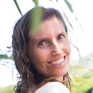 Nikita Timmermans, Steward of Marketing, smiling over her shoulder with wet hair, green foliage behind her.