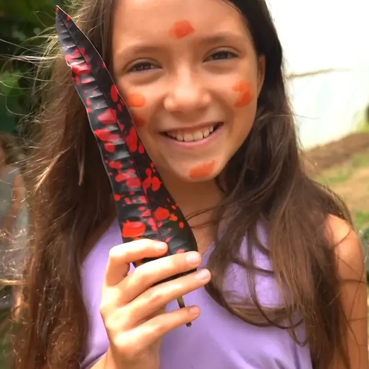 A girl smiling with her harvest from the land at Amora, Dominicalito